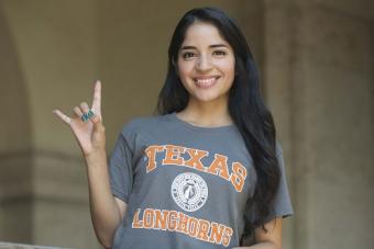 Photo of a UT Austin student showing the Hook 'em Horns hand signal