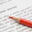 A red pencil making edits on a sheet of written material.